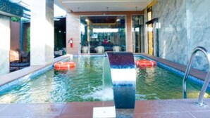 An indoor swimming pool with a modern design, featuring a central water feature and a seating area in the background. - Bayview Resorts And Hotels Lekki (Lekki)