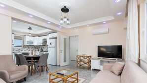 Una sala de estar moderna con sofá, mesa de centro, televisor y comedor.