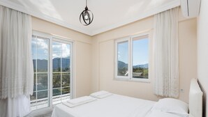 Un dormitorio con una cama grande, dos ventanas y vistas a montañas.