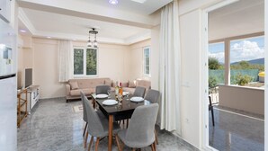 Una sala de estar moderna con comedor, un conjunto de sofás y un balcón con vistas.