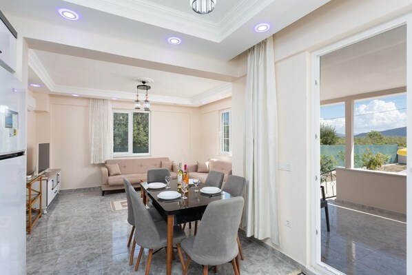 Een moderne woonkamer met een eethoek, een zithoek en een balkon met uitzicht.