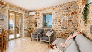 Una habitación con paredes de piedra, un sofá, sillas, una mesa y vistas por una ventana.