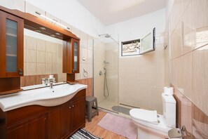 A modern bathroom with a large sink, mirror, and shower.