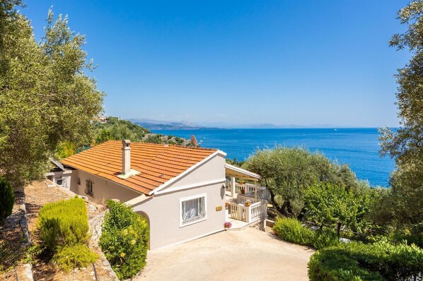 A coastal house with a tiled roof, a balcony, and a view of the sea.