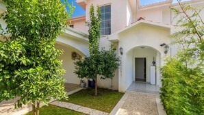 Edifici modern amb un pati cobert, una porta que dona a un espai interior i un petit jardí amb un arbre i arbustos.
