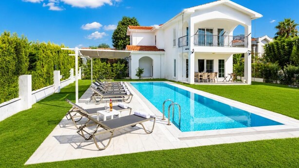 Una casa moderna de dos pisos amb una piscina, un porxo cobert i un jardí ben cuidat.
