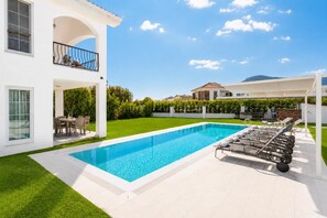 Uma casa moderna de dois andares com piscina, área de estar externa e gramado bem cuidado.