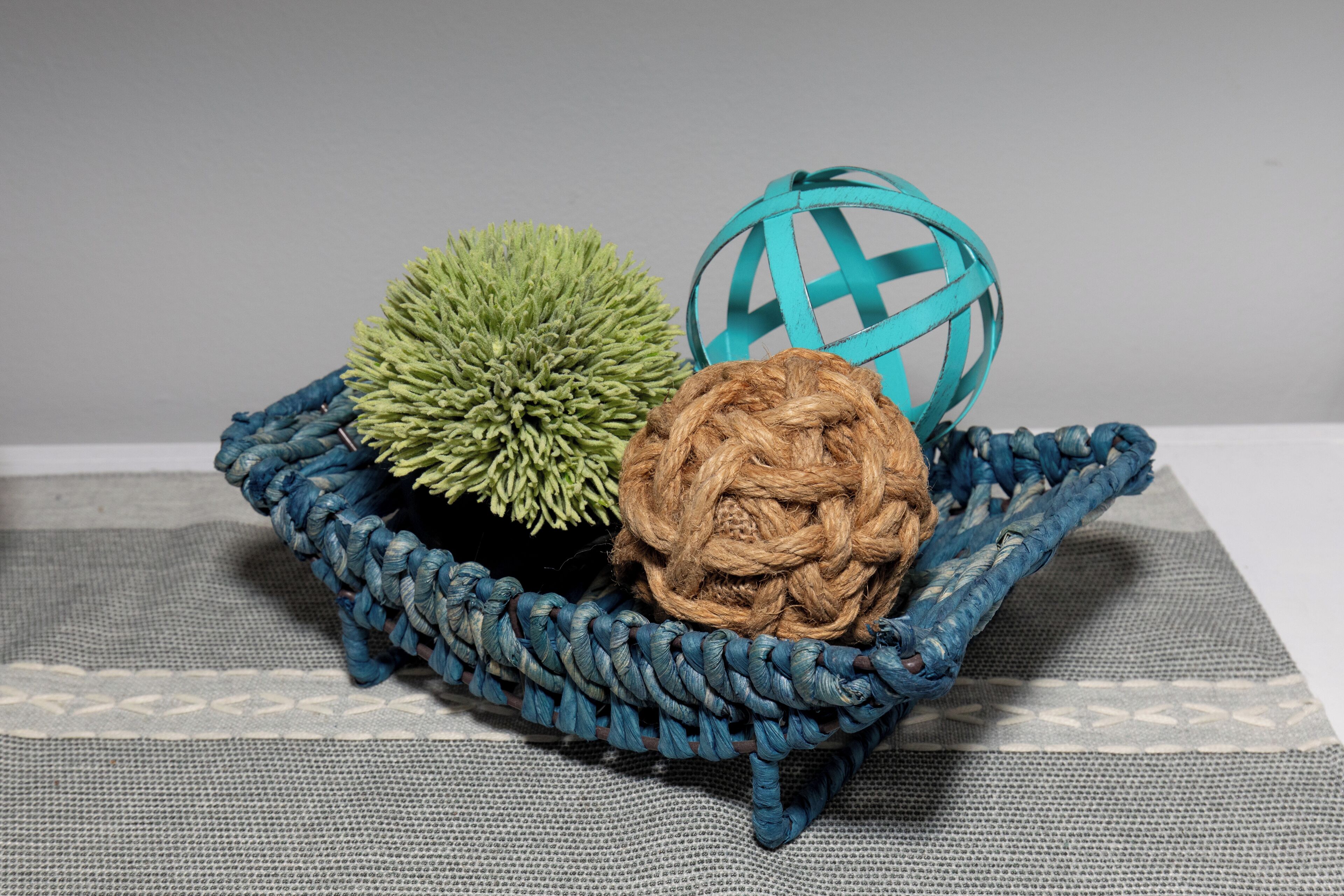 A blue woven basket containing three spherical objects on a textured fabric surface.