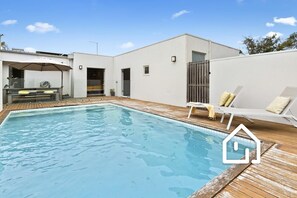A modern pool area with a rectangular pool, wooden deck, and a lounge chair with cushions. - Villa Santorini *1 NIGHT FREE* Secluded Back Beach Poolside Oasis (Blairgowrie)