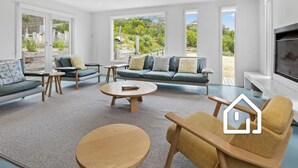 A spacious living room with a sofa set, a coffee table, and a fireplace. - Villa Santorini *1 NIGHT FREE* Secluded Back Beach Poolside Oasis (Blairgowrie)