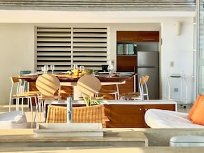 Une cuisine moderne avec un coin repas, comprenant une table dressée pour deux personnes avec des chaises, un réfrigérateur et un four à micro-ondes.