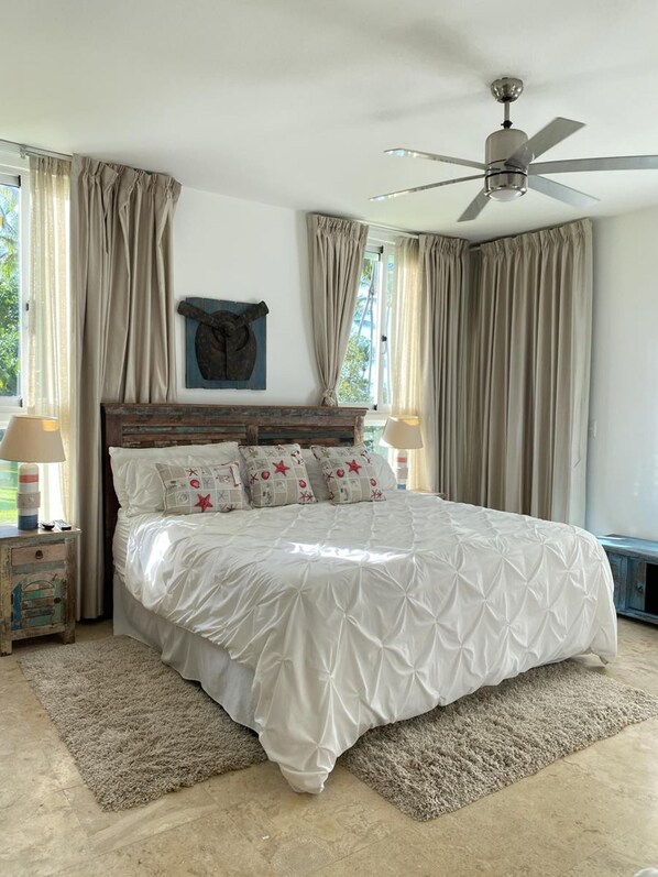 A bedroom with a bed, a ceiling fan, and curtains. - La Ensenada 1 B1 in Juan Dolio (Ramón Santana)