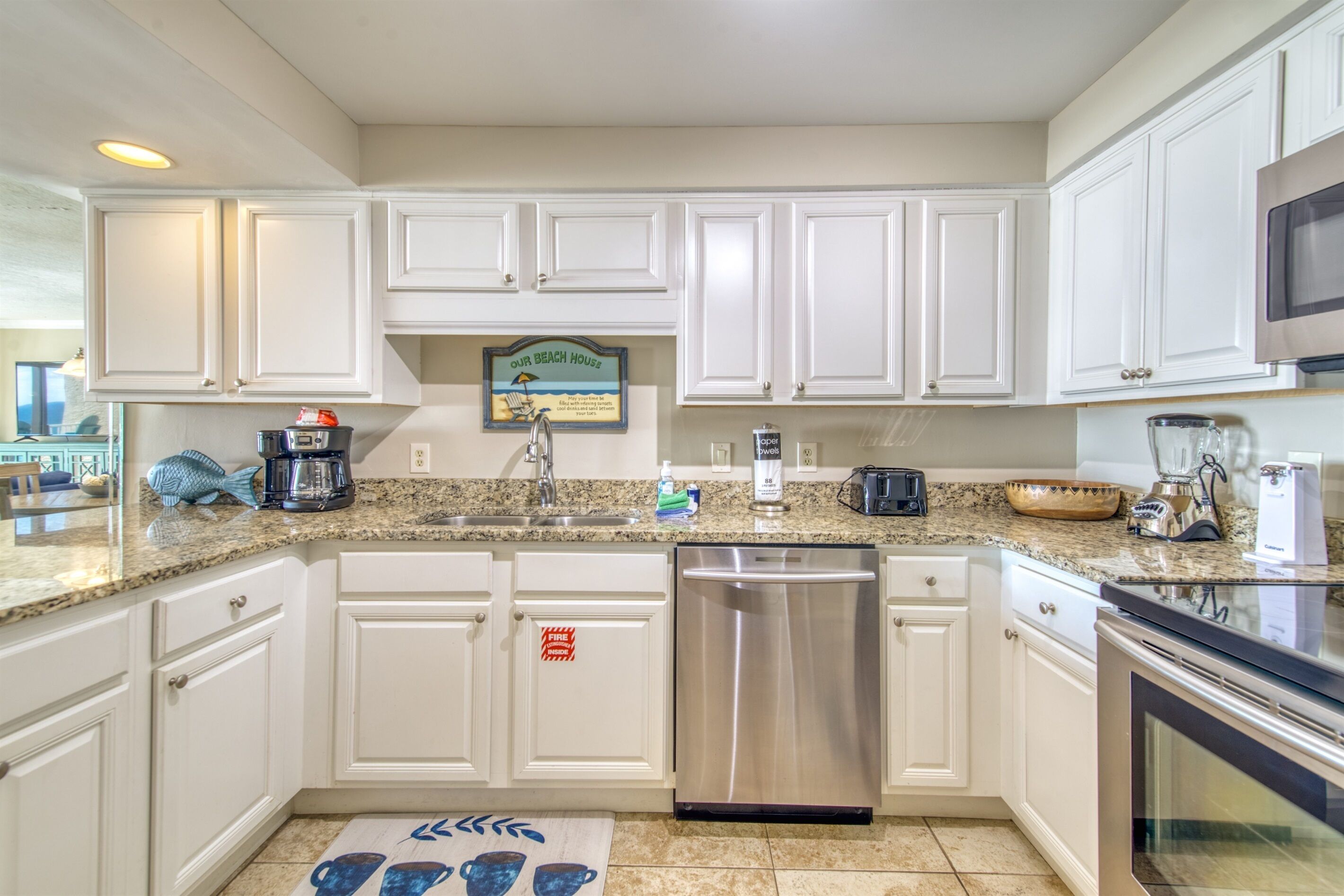 A kitchen with white cabinets, a stainless steel dishwasher, a granite countertop, and a microwave.