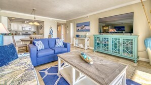 A living room with a blue sofa, a wooden coffee table, and a teal cabinet. - B404 | Beachfront with Beach Service, Pool, & WiFi (Miramar Beach)