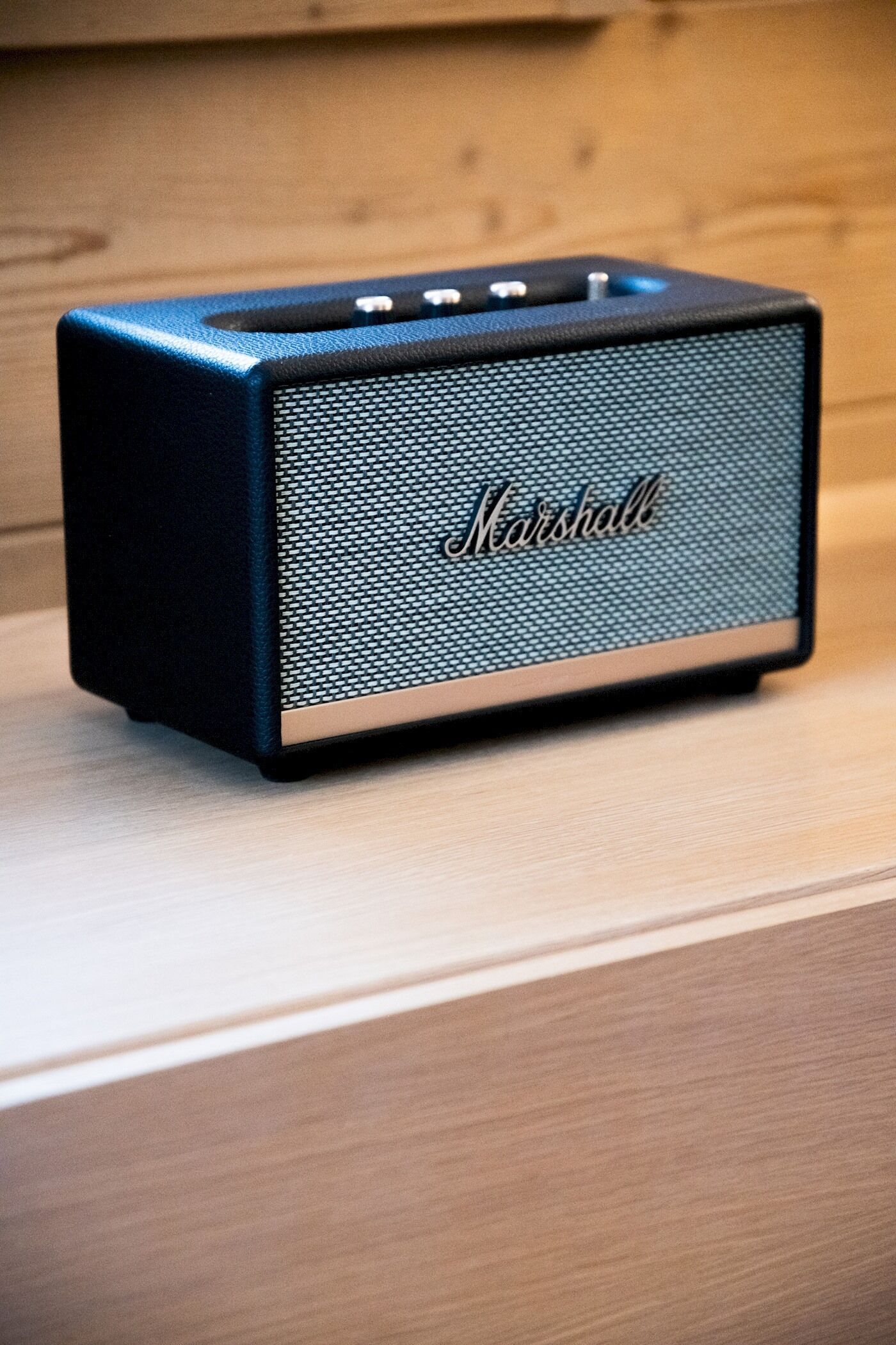 A black Marshall speaker on a wooden surface.