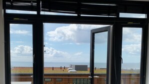Ein Zimmer mit einer großen Schiebeglastür, die auf eine Terrasse mit Meerblick führt.