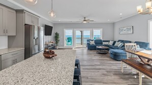 Una cocina amplia con encimeras de granito, una isla central y un comedor con mesa de madera.