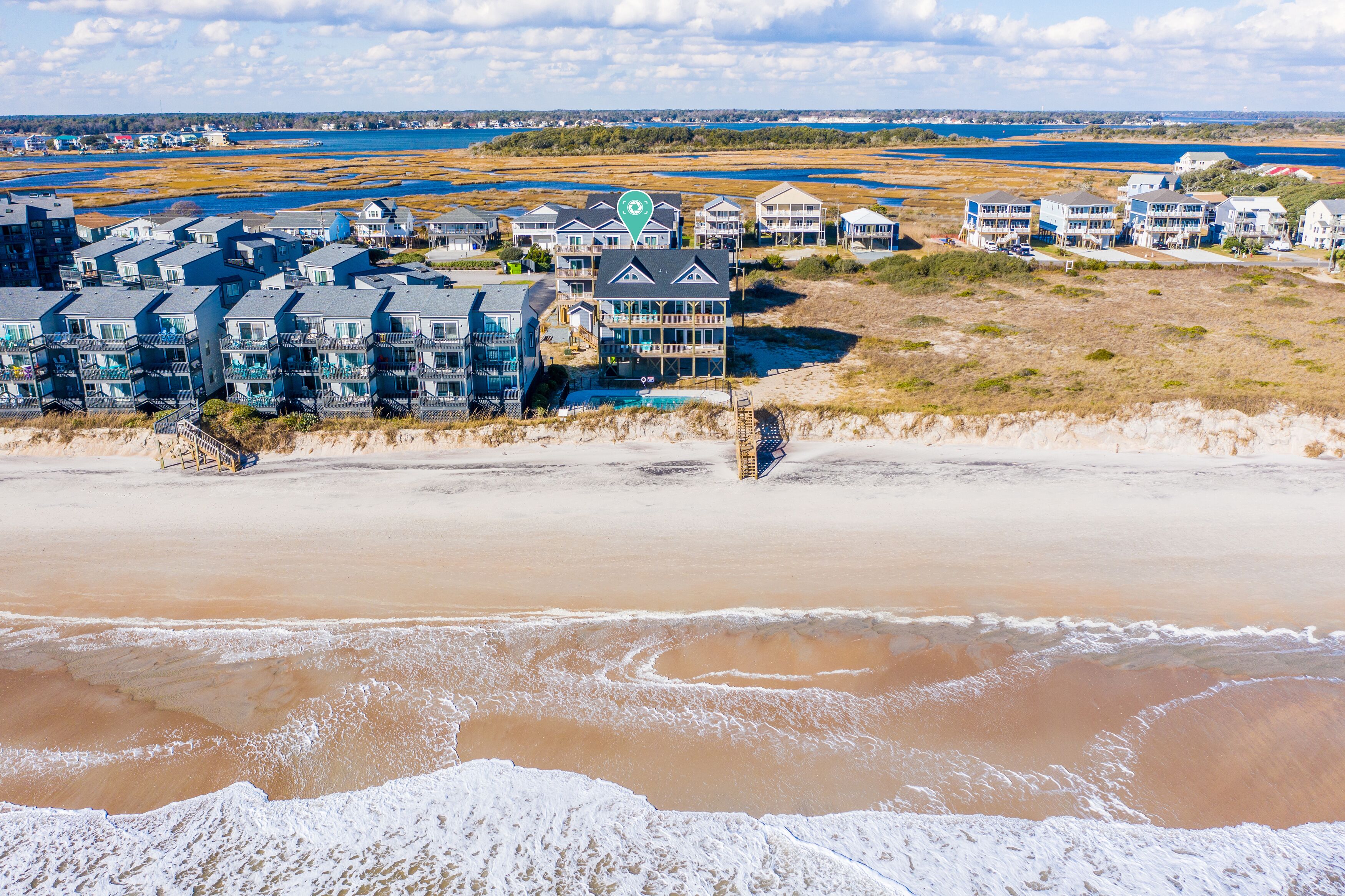 A beachfront hotel with multiple buildings, a pool, and a view of the beach and water.