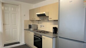 Eine kompakte Küche mit Kühlschrank, Mikrowelle, Herd, Backofen und Kaffeemaschine.