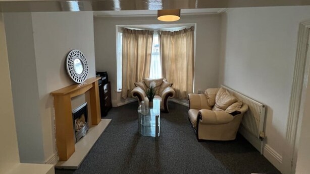Ein Wohnzimmer mit Kamin, Ledersofa und Glastisch.