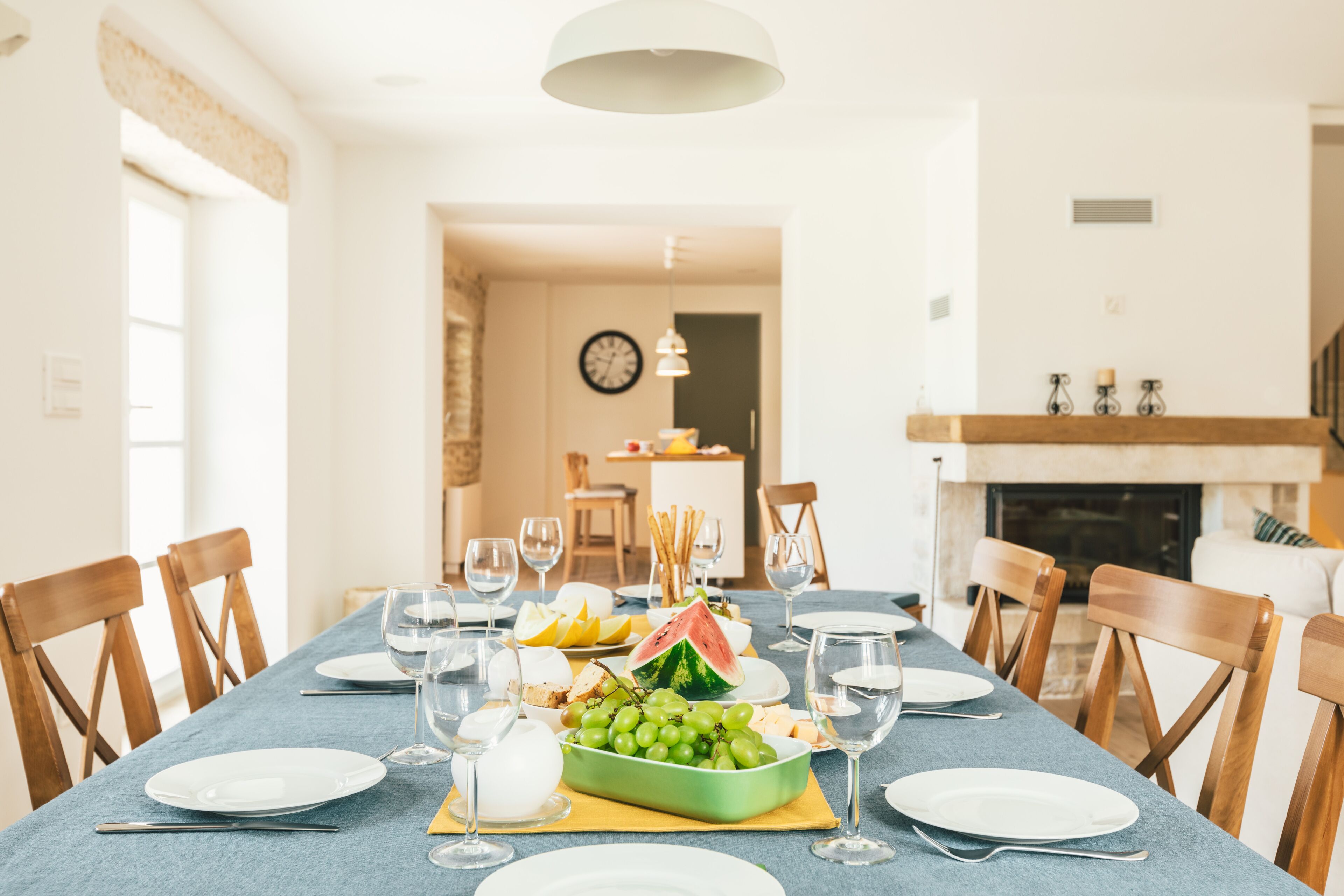 A dining table set with plates, glasses, and a fruit platter.