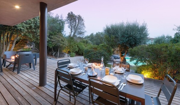Enjoy a meal under the shade of lush greenery with a view of the pool.