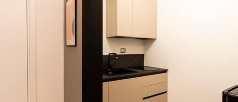 Une cuisine compacte avec un évier noir, des armoires de couleur beige et un petit plan de travail.
