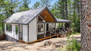 A cabin with a sloped roof, a deck, and a large window. - Alpine Amorè in Hochatown/Broken Bow, OK (Broken Bow)