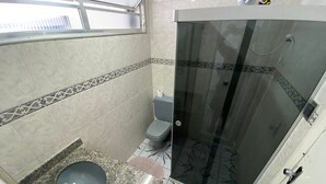Un baño con inodoro, lavamanos y cabina de ducha.