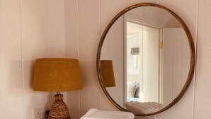 Une commode blanche avec un miroir et une lampe.