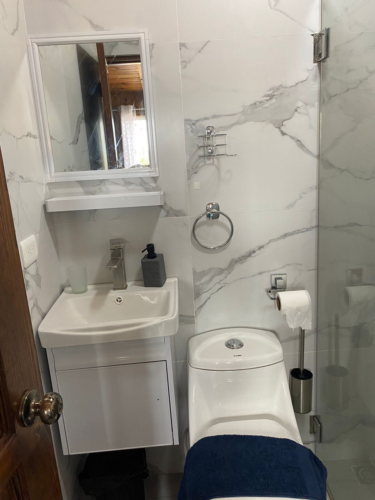 A bathroom with a white sink, mirror, and toilet.