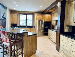 A kitchen with wooden cabinets, a stainless steel refrigerator, a built-in oven, and a large window. - Ski-In/Out 5 BR House at Copper Mtn (Frisco)
