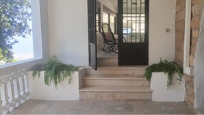 A staircase leading to a door with a metal gate, flanked by two potted plants. - Beit Nemer Chemlan Arch house private garden sunset valley view 24/7 Electricity (Chemlan)