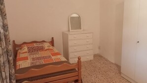 A bedroom with a wooden bed, a white dresser with drawers, a mirror, and a closed door. - Beit Nemer Chemlan Arch house private garden sunset valley view 24/7 Electricity (Chemlan)