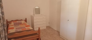 A bedroom with a wooden bed, a white dresser with drawers, a mirror, and a closed door. - Beit Nemer Chemlan Arch house private garden sunset valley view 24/7 Electricity (Chemlan)
