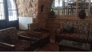 A cozy seating area with patterned sofas and armchairs, a coffee table, and a stone accent wall. - Beit Nemer Chemlan Arch house private garden sunset valley view 24/7 Electricity (Chemlan)