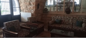 A cozy seating area with patterned sofas and armchairs, a coffee table, and a stone accent wall. - Beit Nemer Chemlan Arch house private garden sunset valley view 24/7 Electricity (Chemlan)
