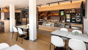 Een modern restaurant in een hotel, met een buffet, witte stoelen en een bar.