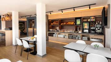 En moderne restaurant i et hotel med et buffetbord, hvide stole og en bar.