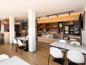 A modern hotel restaurant with a buffet area, white chairs, and a bar. - B&B HOTEL Magdeburg-Barleben (Barleben)