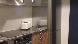 A modern kitchen with stainless steel appliances, wooden cabinets, and pendant lighting.