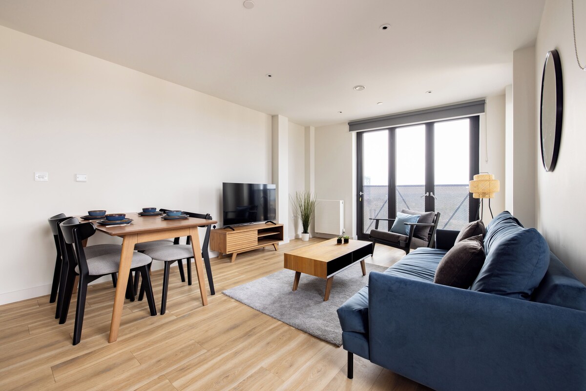 Una sala moderna con un sofá, una mesa de comedor con sillas, un televisor y un ventanal grande.