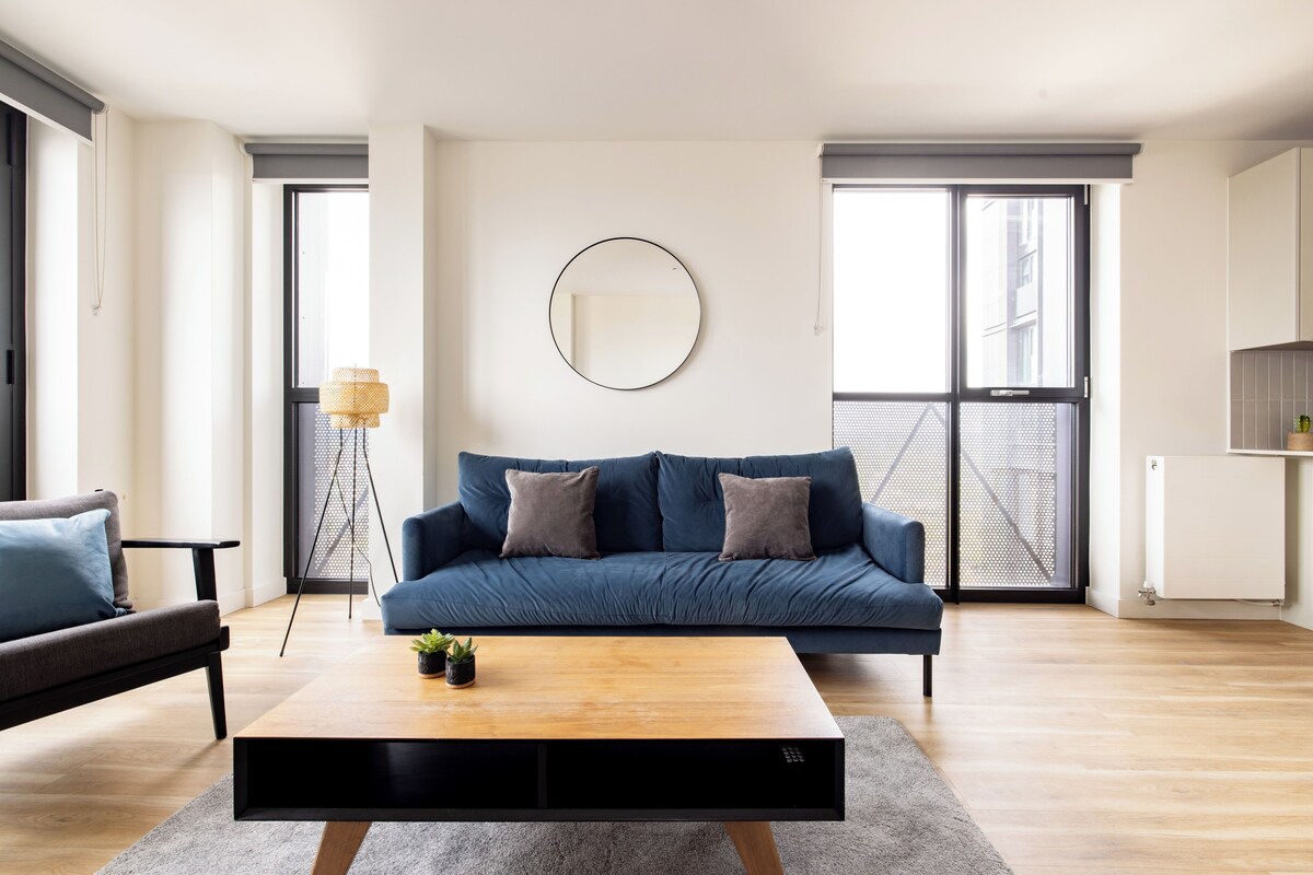 A modern living room with a blue sofa, a coffee table, and a large window.