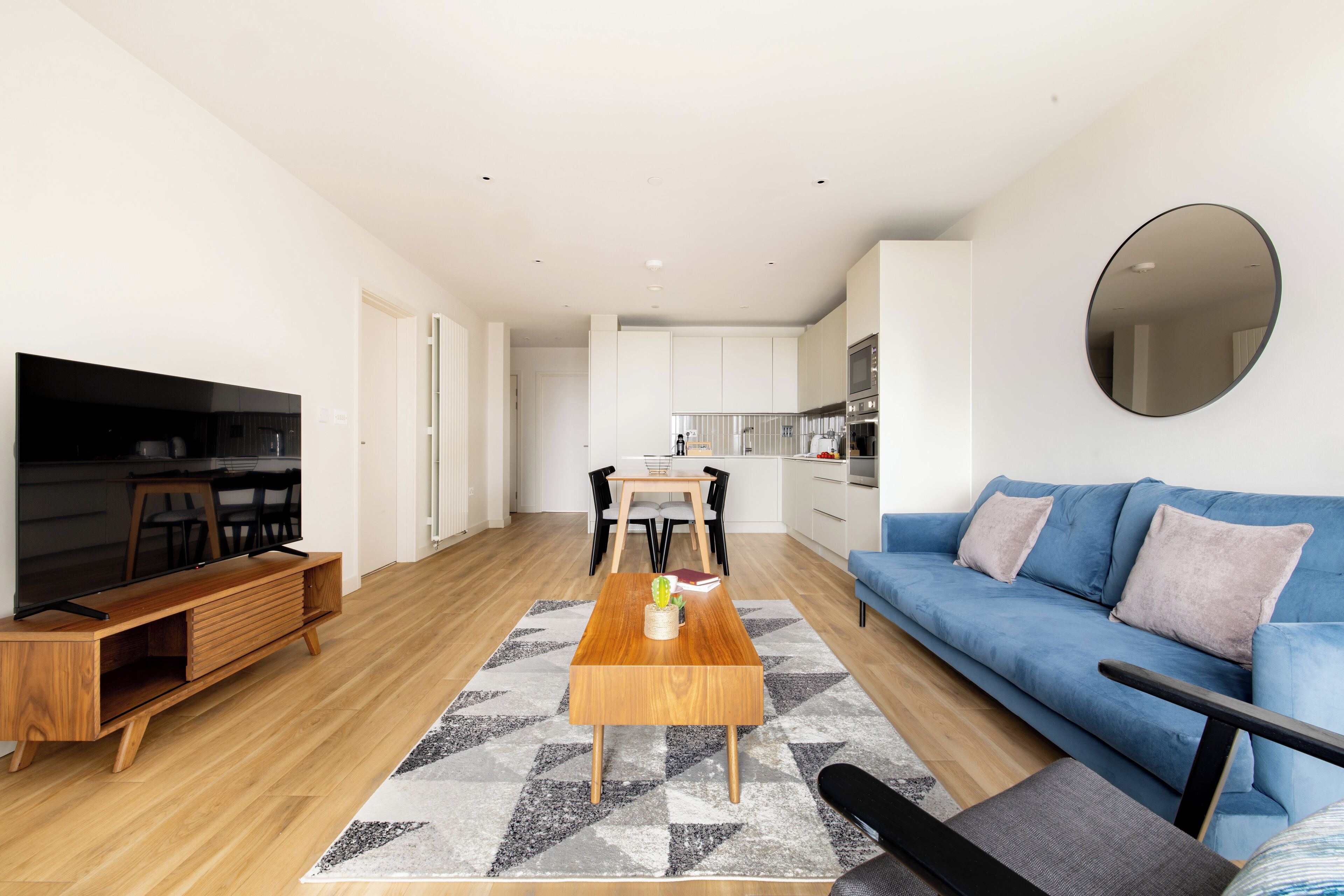 A modern living room with a TV, sofa, coffee table, and dining area.