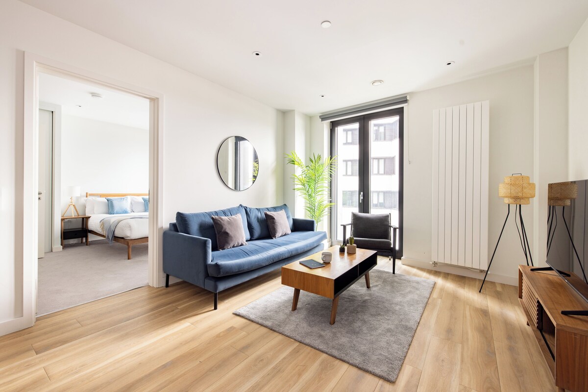 Una sala de estar moderna con un sofá azul, una mesa de centro de madera y un espejo grande.