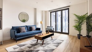A modern living room with a blue sofa, a wooden coffee table, and a large mirror on the wall. - Croydon by Charles Hope (Croydon)