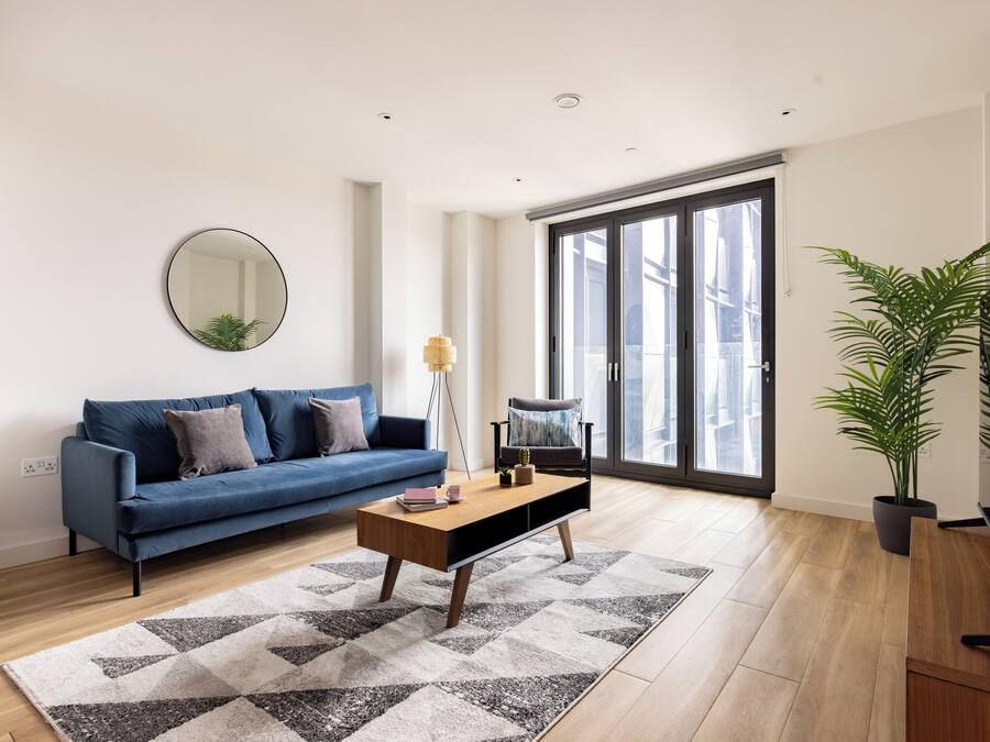 Un soggiorno moderno con un divano blu, un tavolino in legno e un grande specchio a parete.