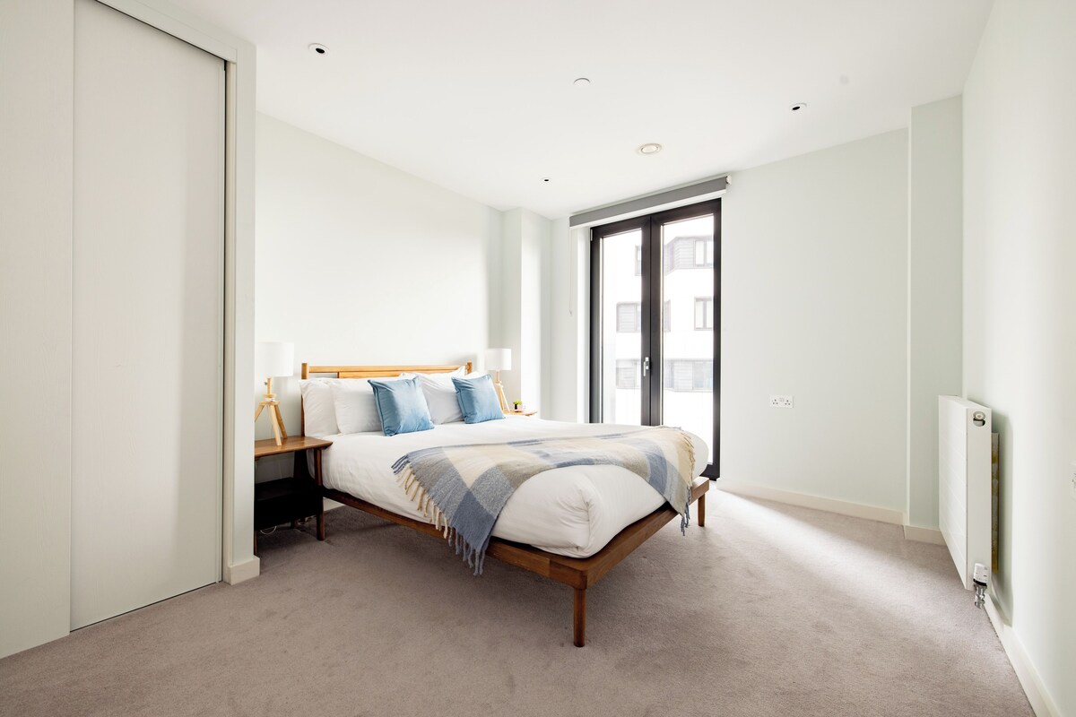 A bedroom with a bed, bedside tables, a window, and a radiator.