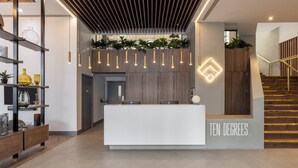 A reception desk with a sign reading "TEN DEGREES" and a staircase with wooden railings. - Croydon by Charles Hope (Croydon)