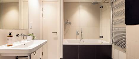 A modern bathroom with a white sink, a bathtub, and a shower.